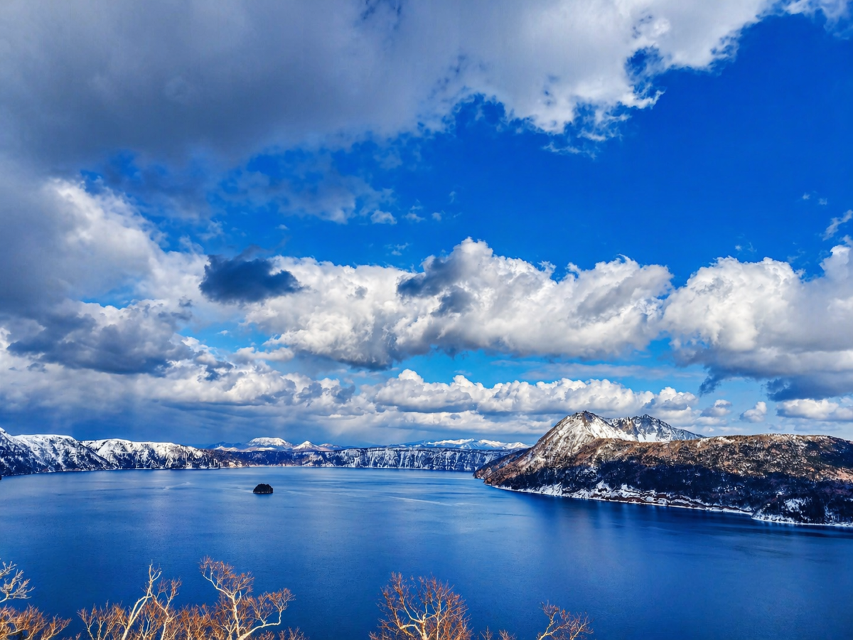 冬の摩周湖、青い湖面と雪山の風景