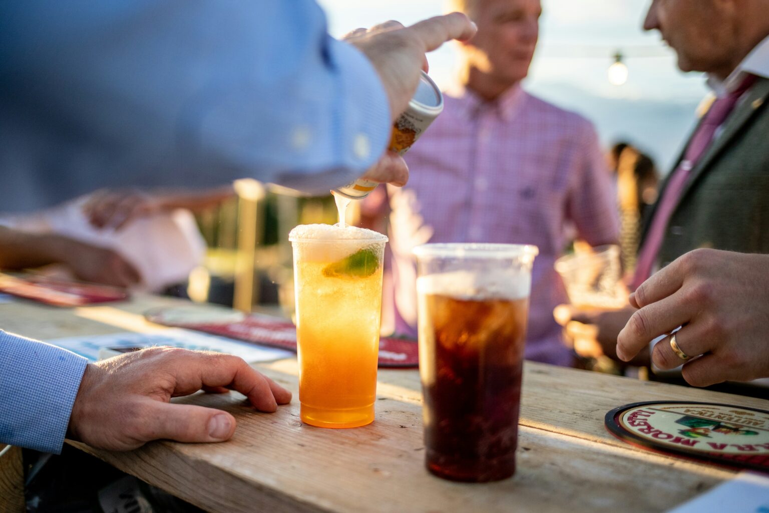 飲み物が並ぶ木製テーブルを囲む友人たちの手元（転職活動で3種類のアドバイスを受けた27歳のイメージ）